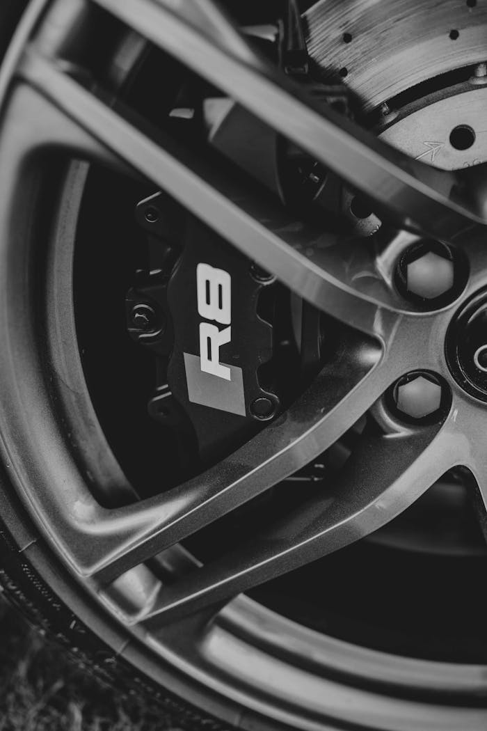 hero-img-01 Detailed view of a car brake caliper and wheel rim in black and white.