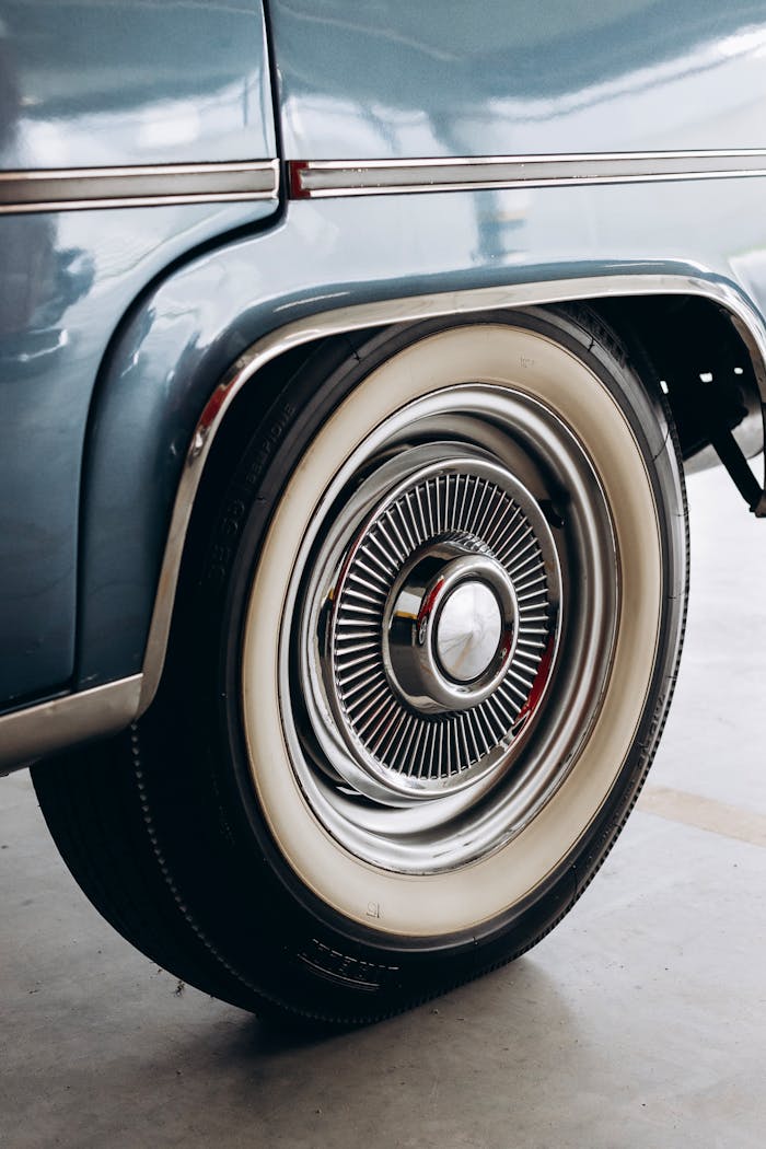 gallery-4 Detailed close-up of a classic vintage car's rear wheel featuring a whitewall tire and chrome hubcap.