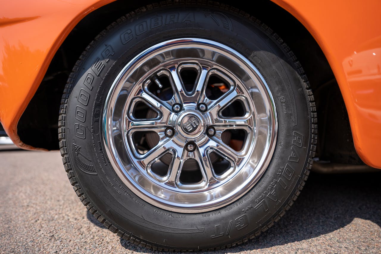 our-services-2 Close-up of a chrome wheel on a classic orange car, showcasing vintage style.