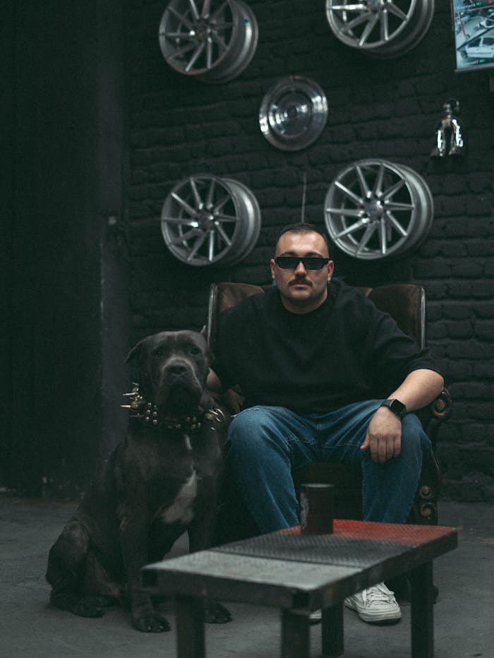 our-services-3 Man seated with strong dog in industrial room with wheel decor.