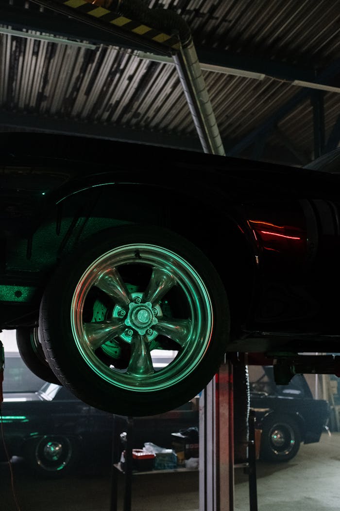about-01 Close-up of a car wheel illuminated by neon lights in a garage.